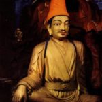 A golden color statue of King Songstsen Gampo with a red hat